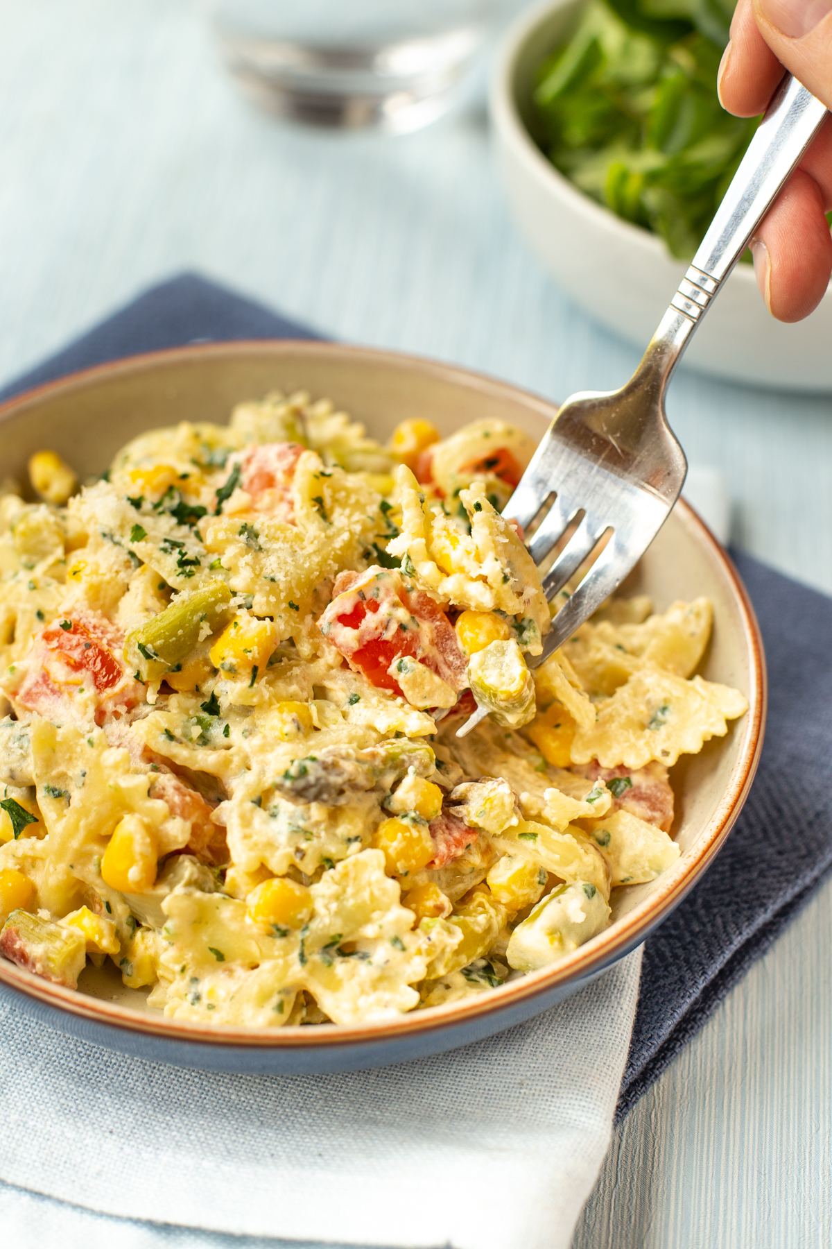 A fork taking a scoop of pasta primavera from a bowl.