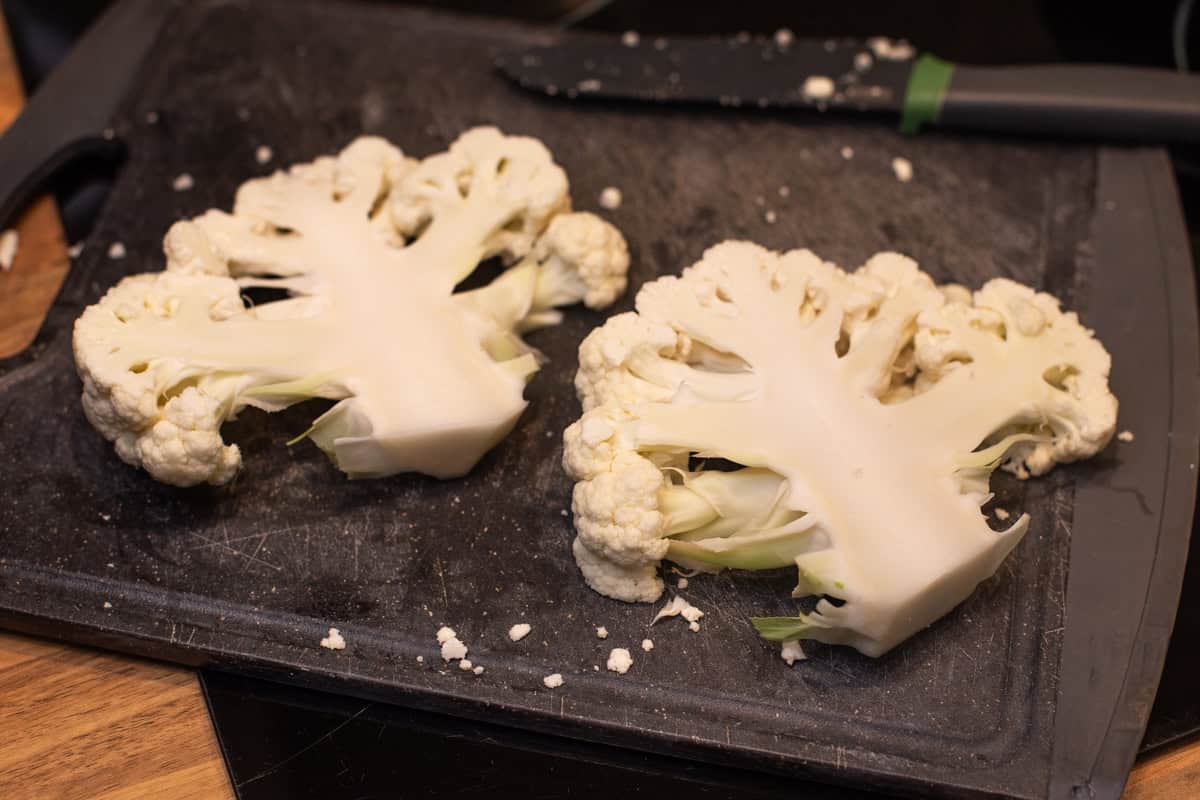 Thick cauliflower steaks on a cutting board.