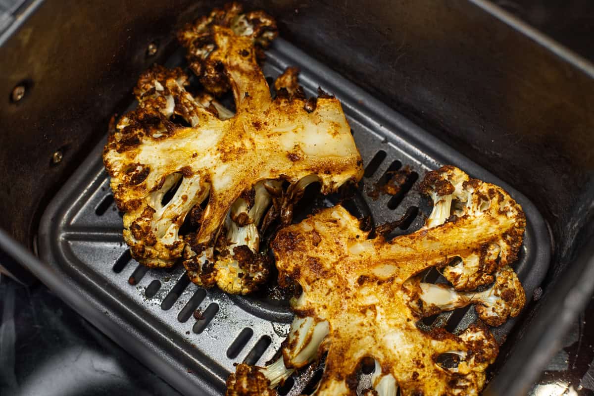 Cooked marinated cauliflower steaks in an air fryer.