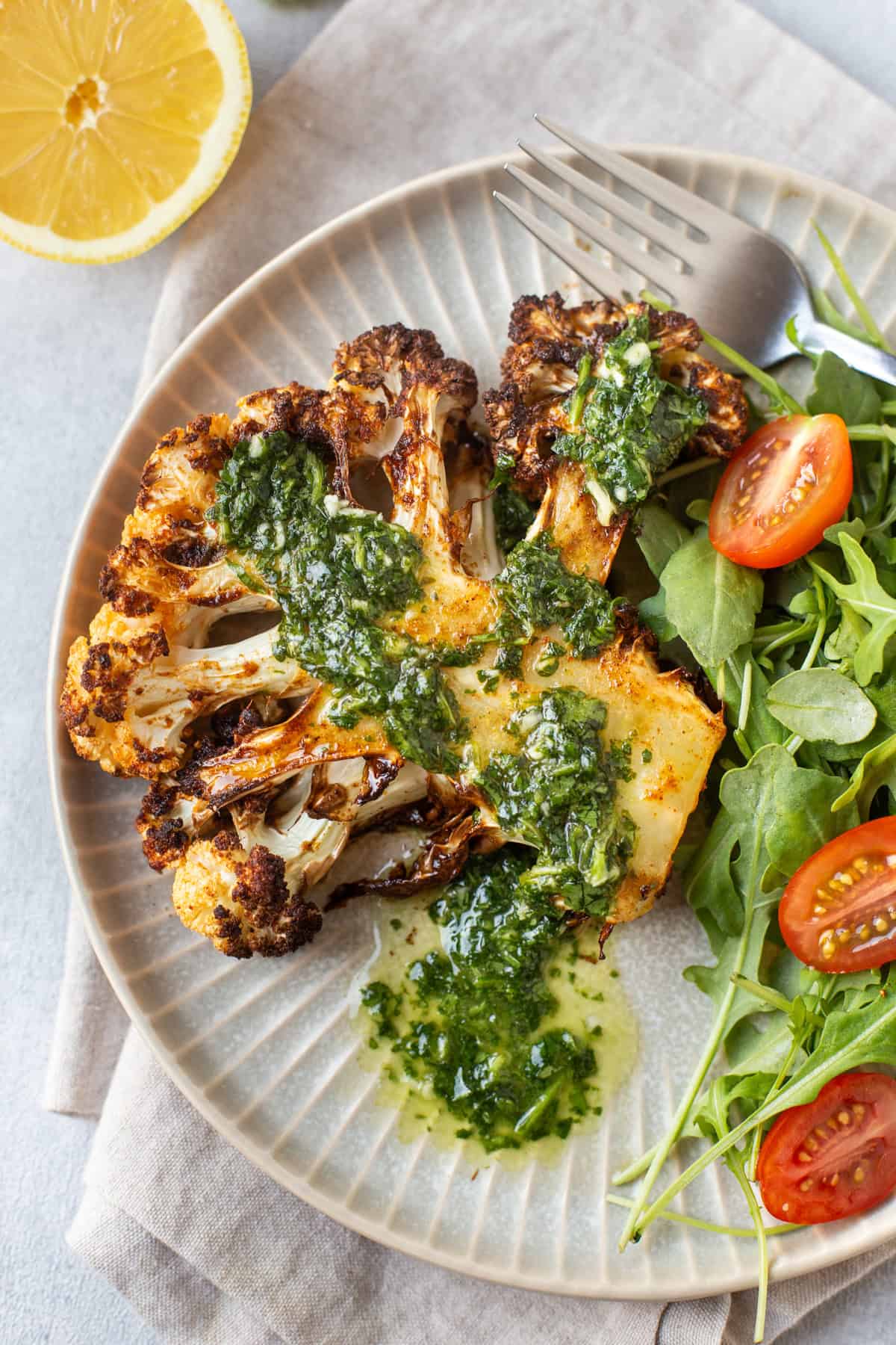 A cauliflower steak cooked in an air fryer, served with dressing and salad.