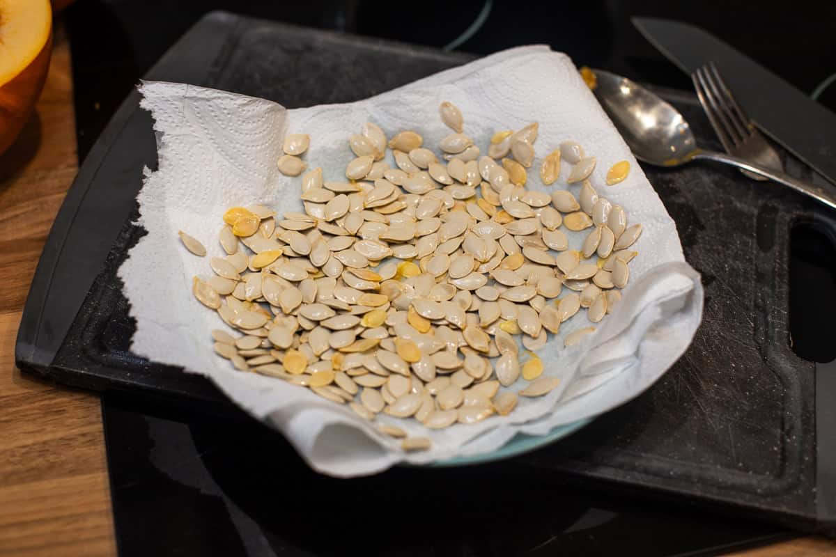 Raw pumpkin seeds spread out on a piece of kitchen paper.