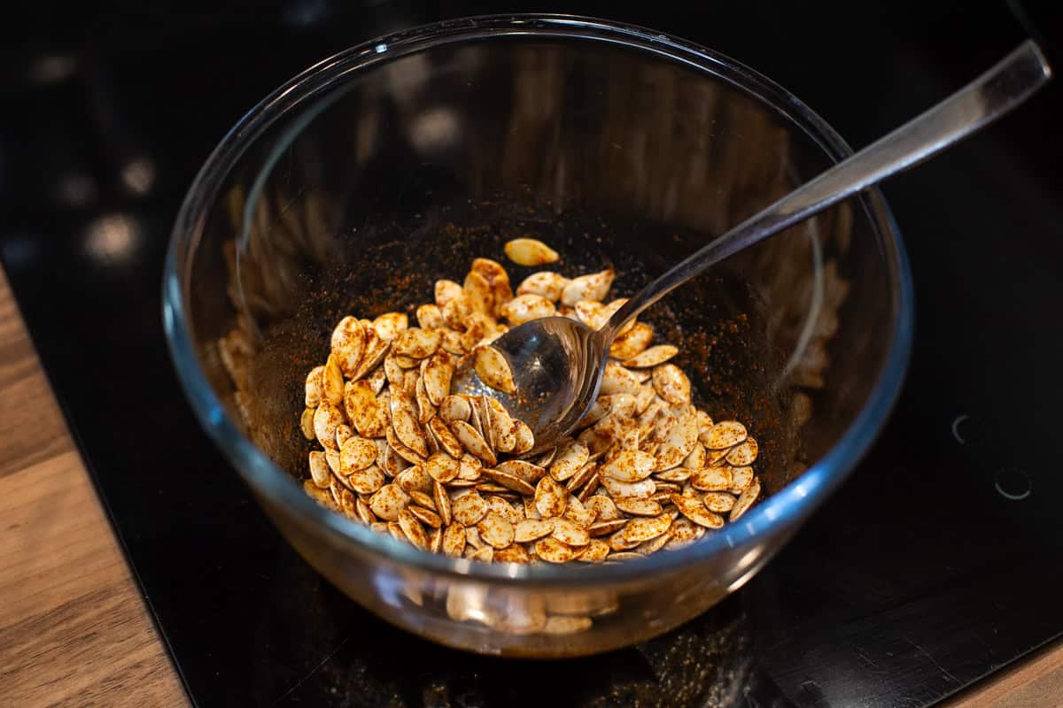 Pumpkin seeds in a bowl mixed with spices and salt.