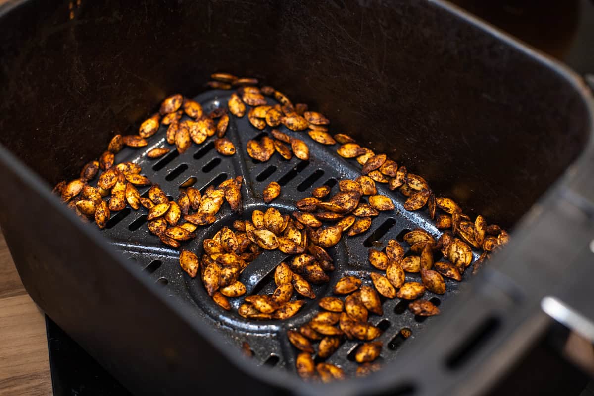 Toasted pumpkin seeds in an air fryer basket.