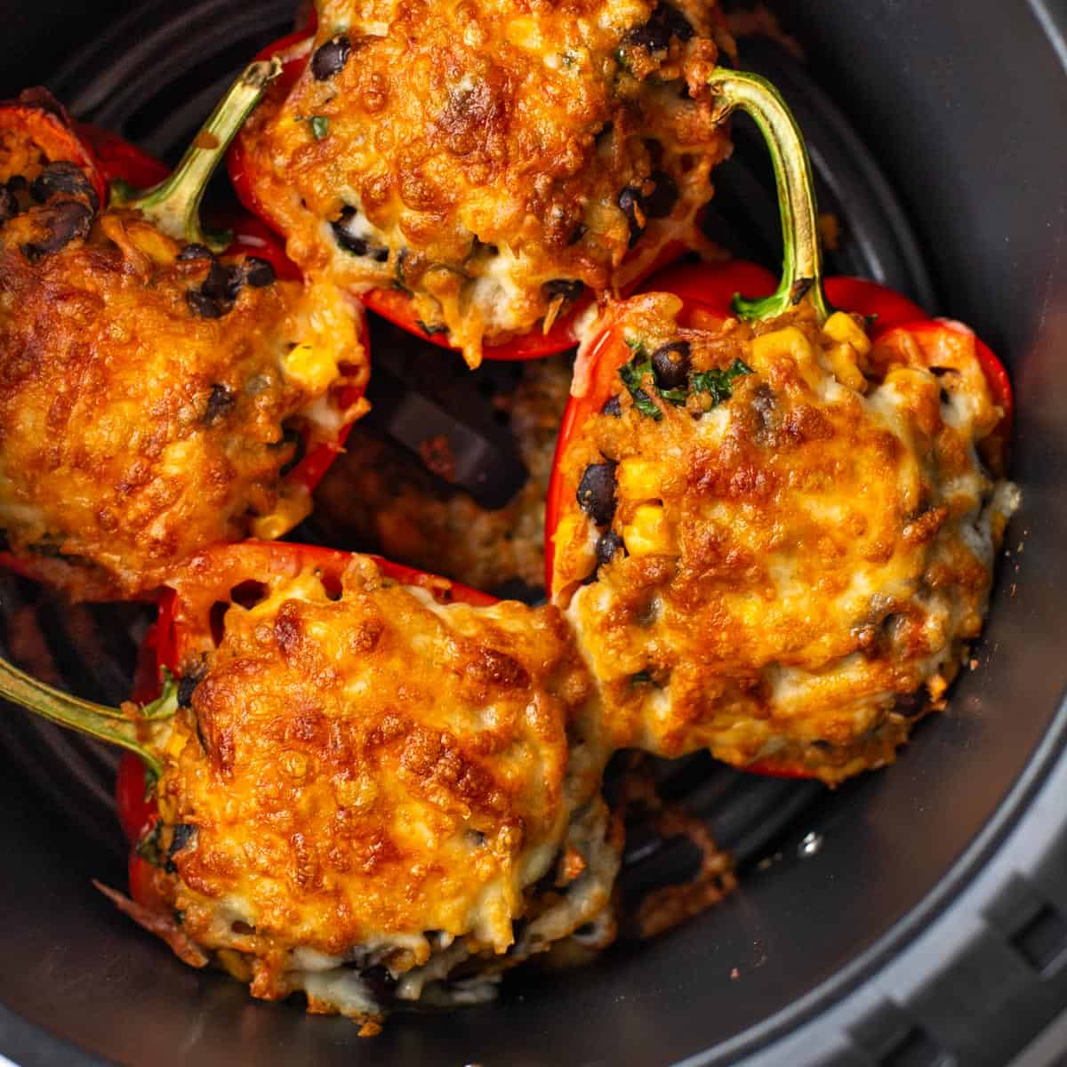 Cheesy vegetarian stuffed peppers in an air fryer basket.