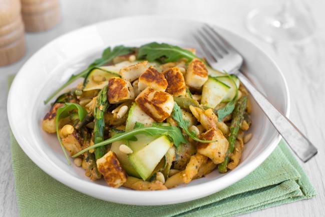 A bowl of pesto pasta with asparagus and crispy fried halloumi.