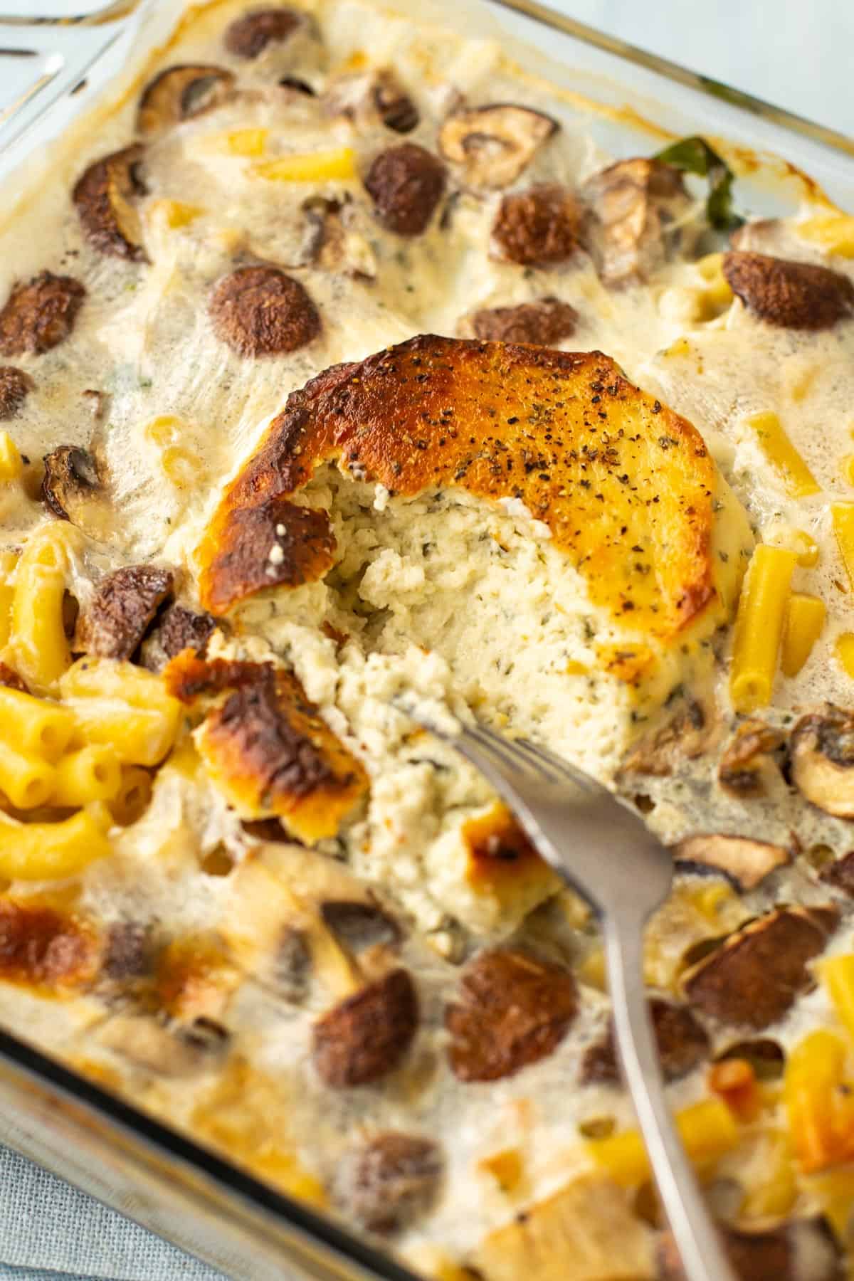 Crispy baked Boursin cheese being crumbled into baked pasta.