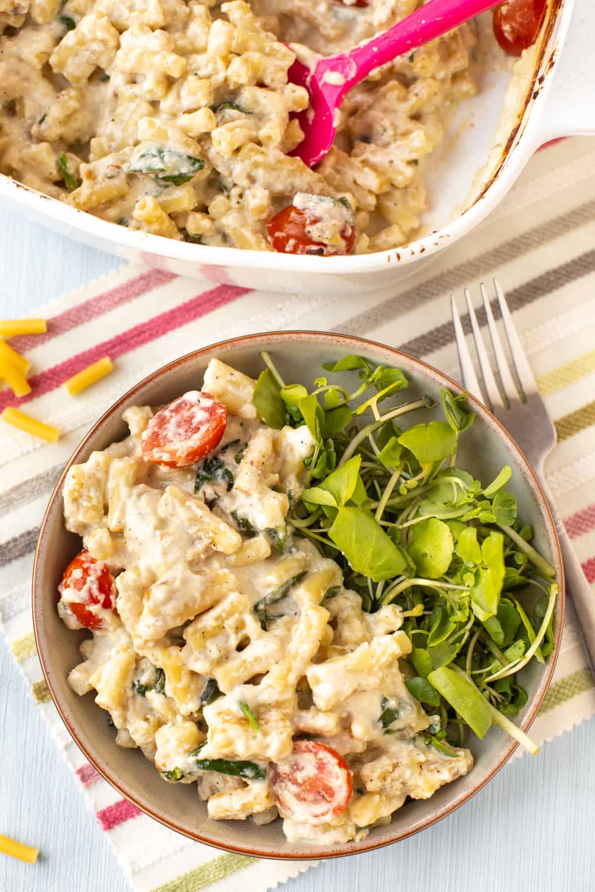 A portion of mac and cheese in a bowl with fresh watercress.
