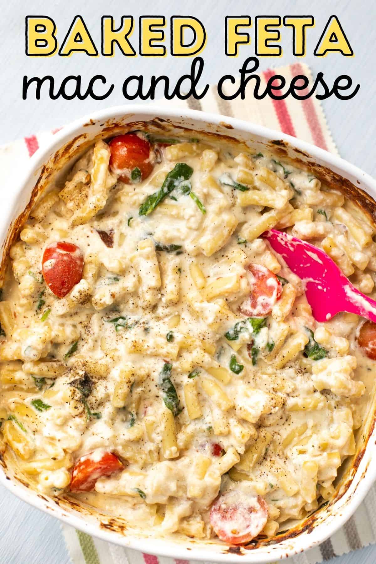 Cheesy baked mac and cheese in a baking dish with spinach and tomatoes.
