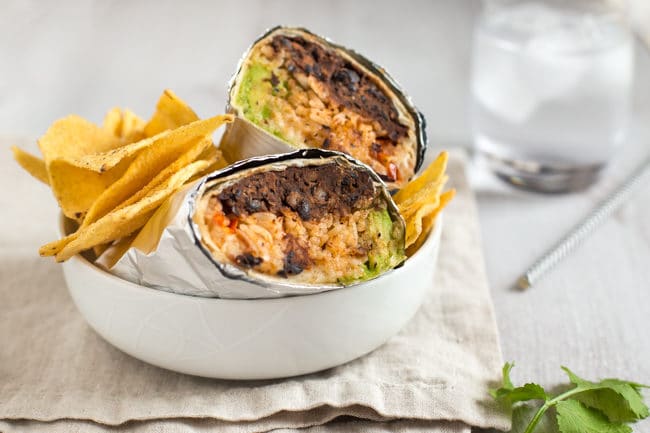 BBQ bean burritos wrapped in foil, served in a bowl with tortilla chips