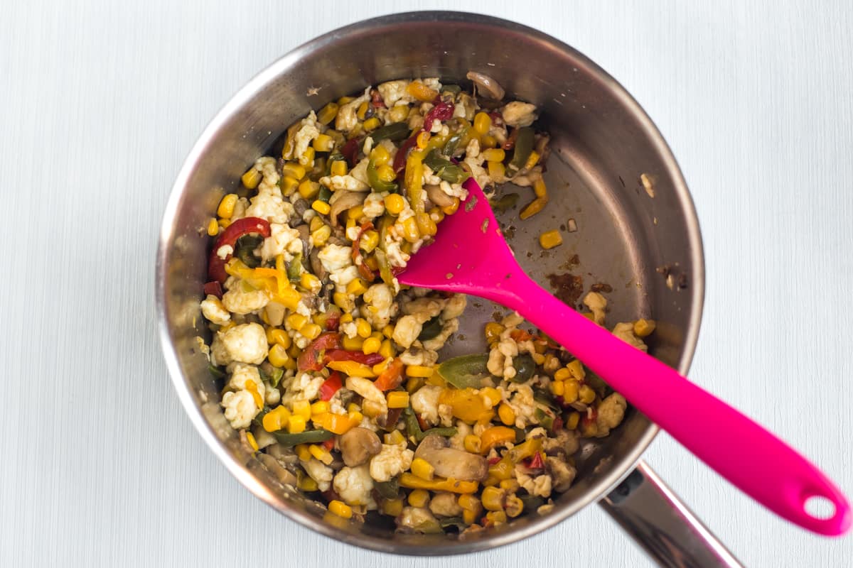 Vegetables and crumbled halloumi cheese in a saucepan.
