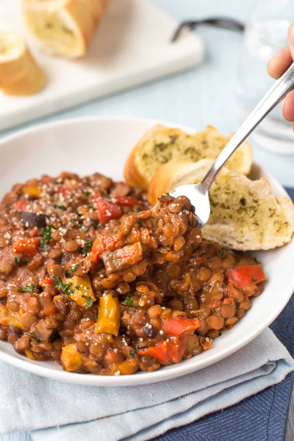 Cheesy lentils and garlic bread being scooped with a fork.