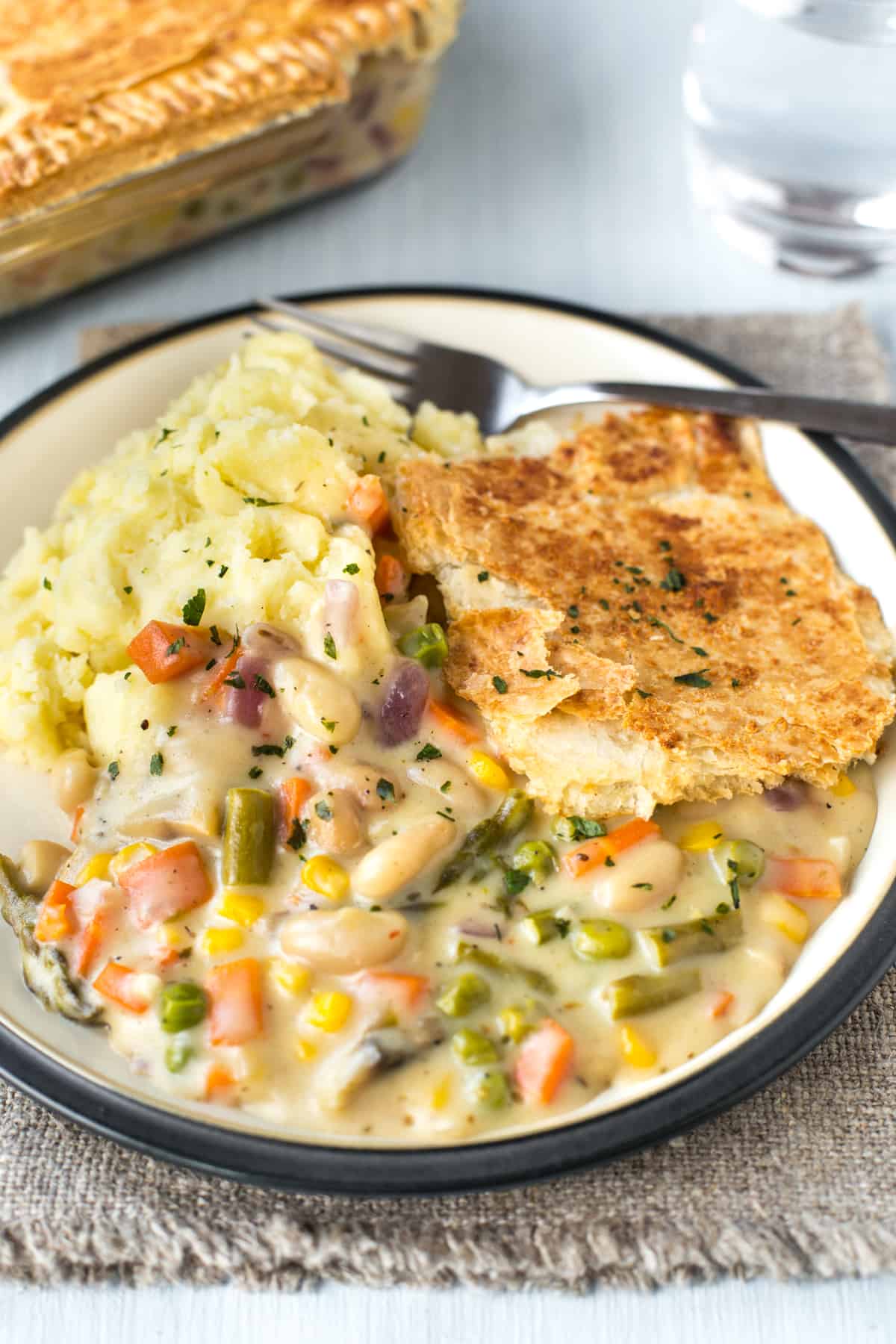 A portion of colourful vegetable pie with cheese sauce.