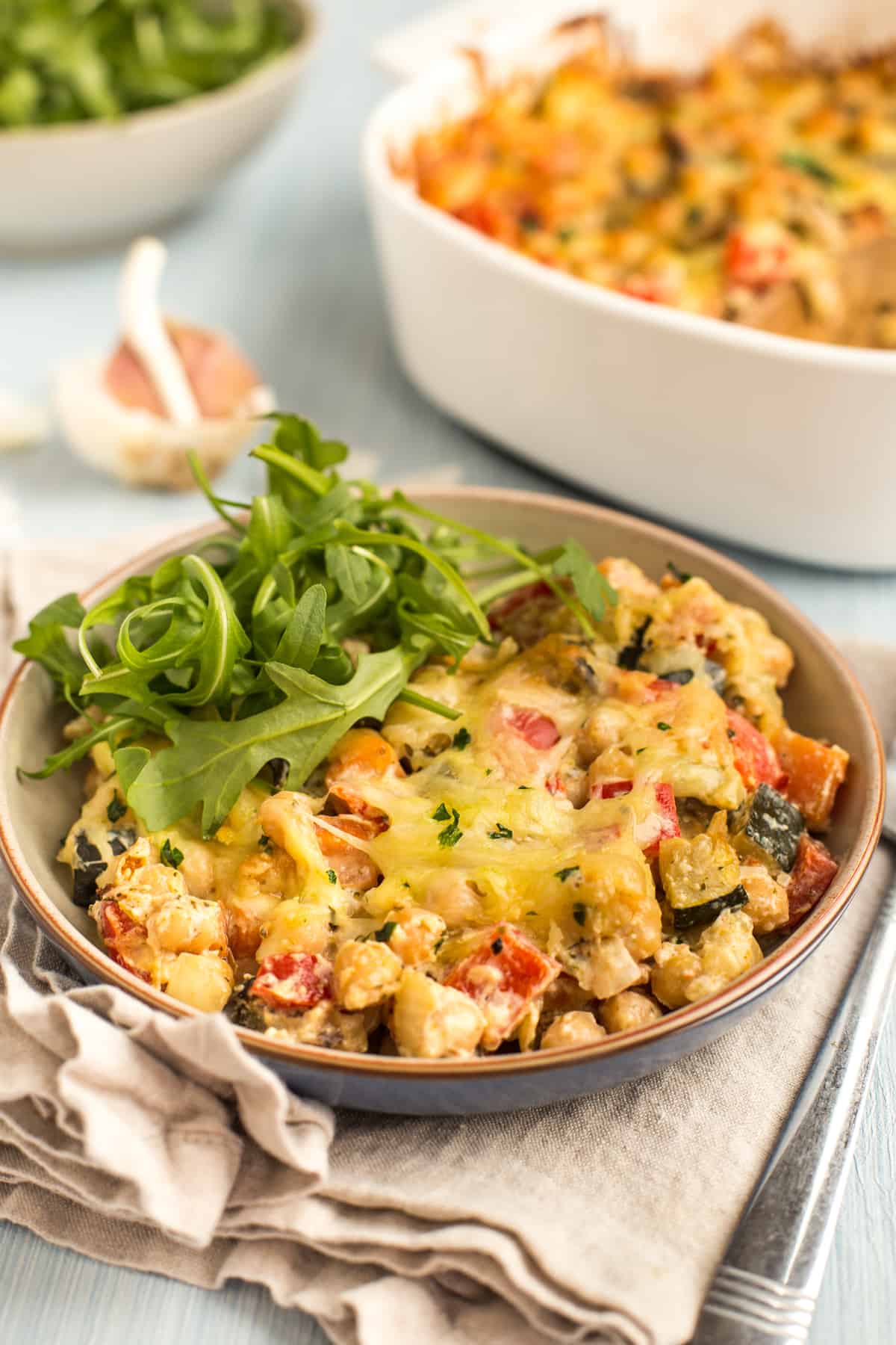 Portion of creamy chickpea bake in a bowl served with fresh rocket.