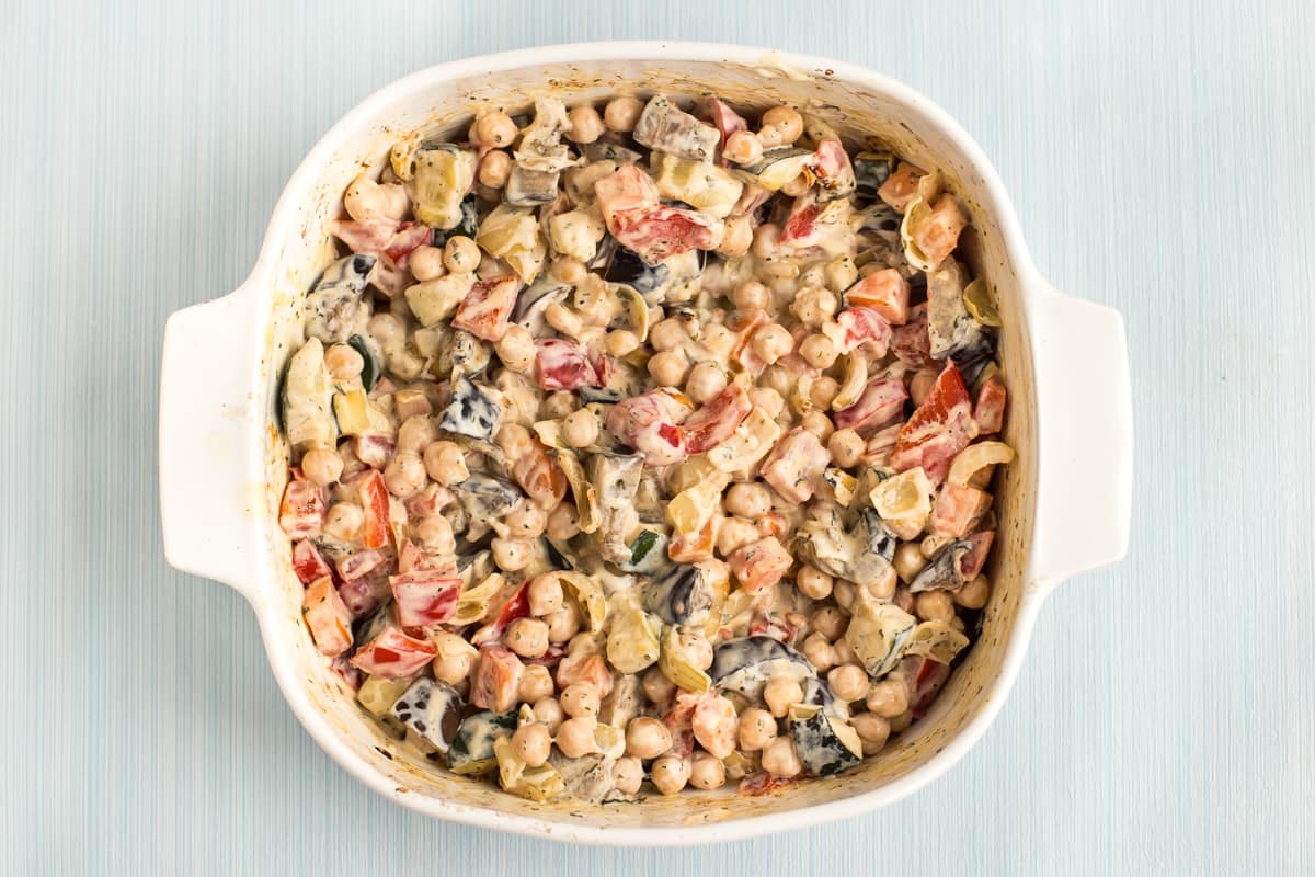 Roasted vegetables in a creamy sauce in a baking dish.