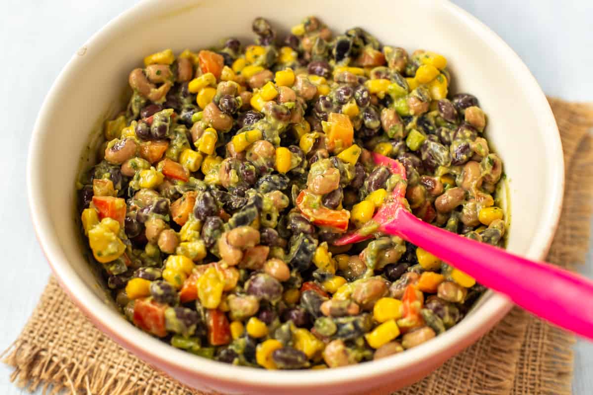 Creamy cowboy caviar with avocado dressing in a mixing bowl.