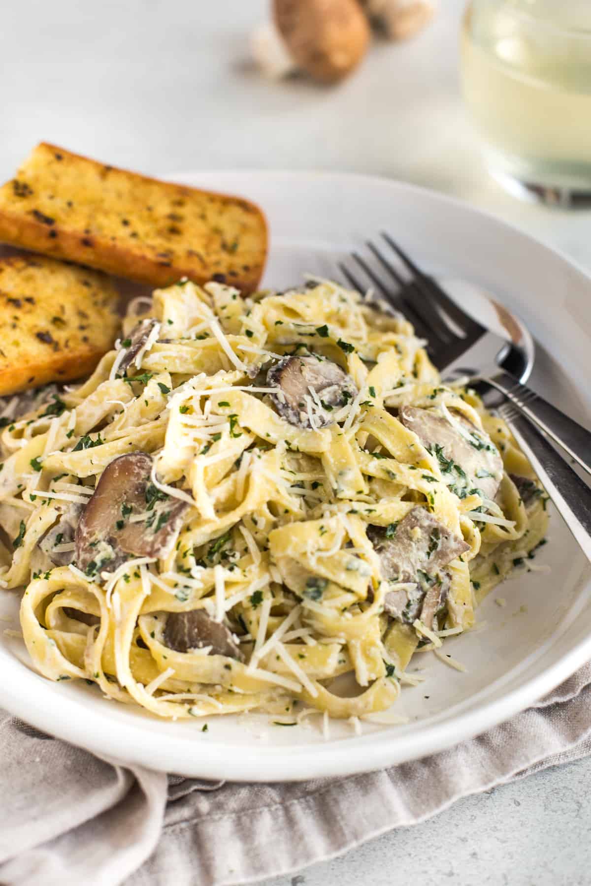 Garlic mushroom tagliatelle with garlic bread in a bowl.