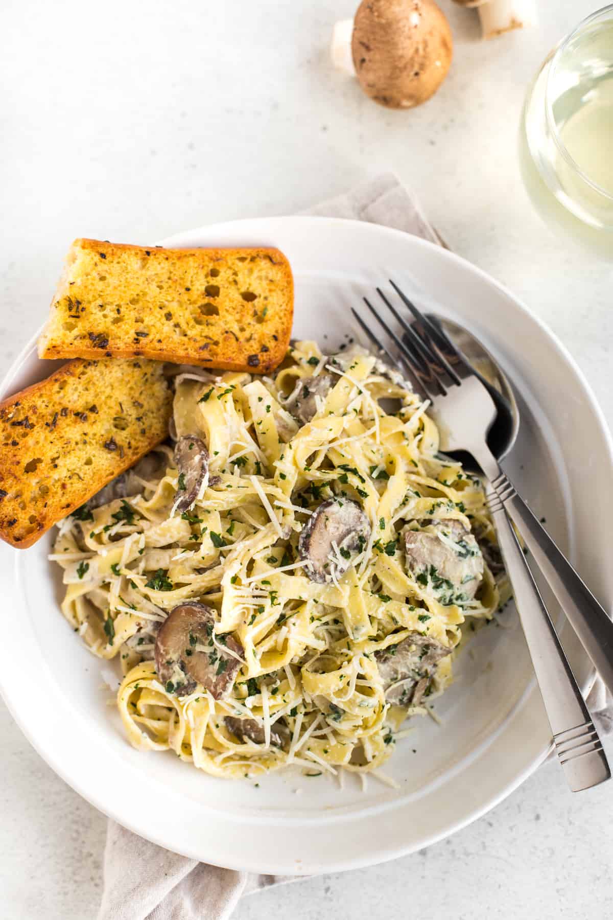 Creamy garlic mushroom tagliatelle in a bowl with garlic bread.