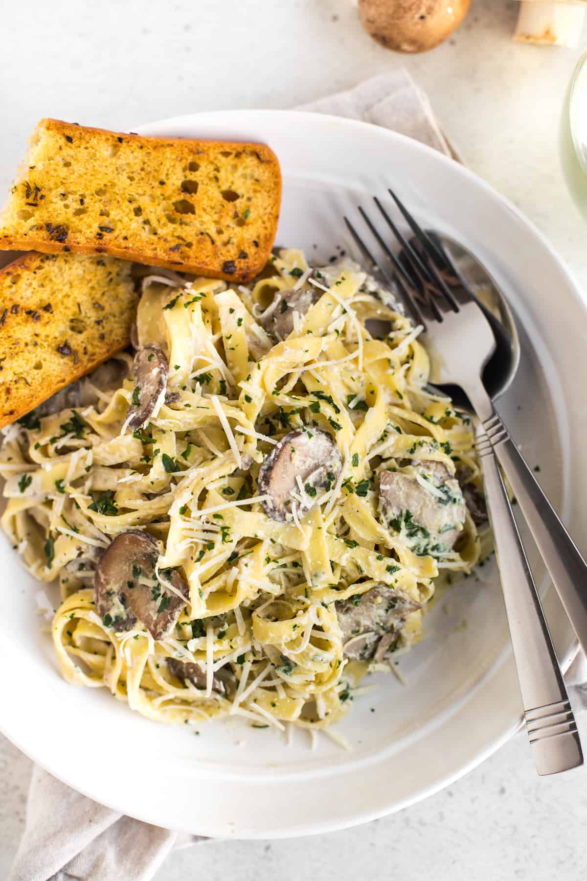 Portion of creamy garlic mushroom tagliatelle in a bowl, topped with parmesan and parsley.