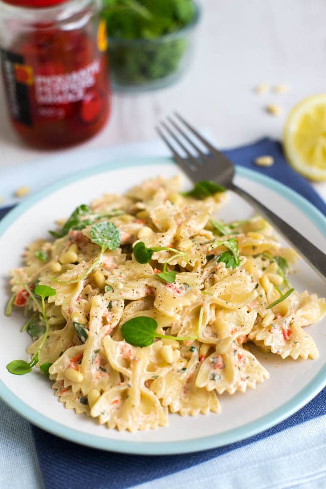 A portion of creamy pasta on a plate, topped with watercress.