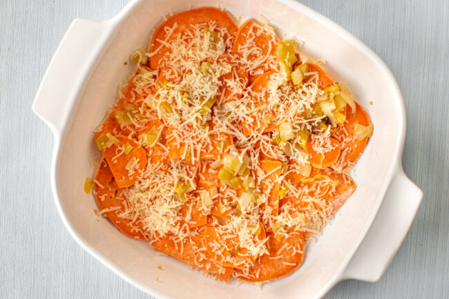 Sweet potato, leeks and parmesan cheese in a baking dish.