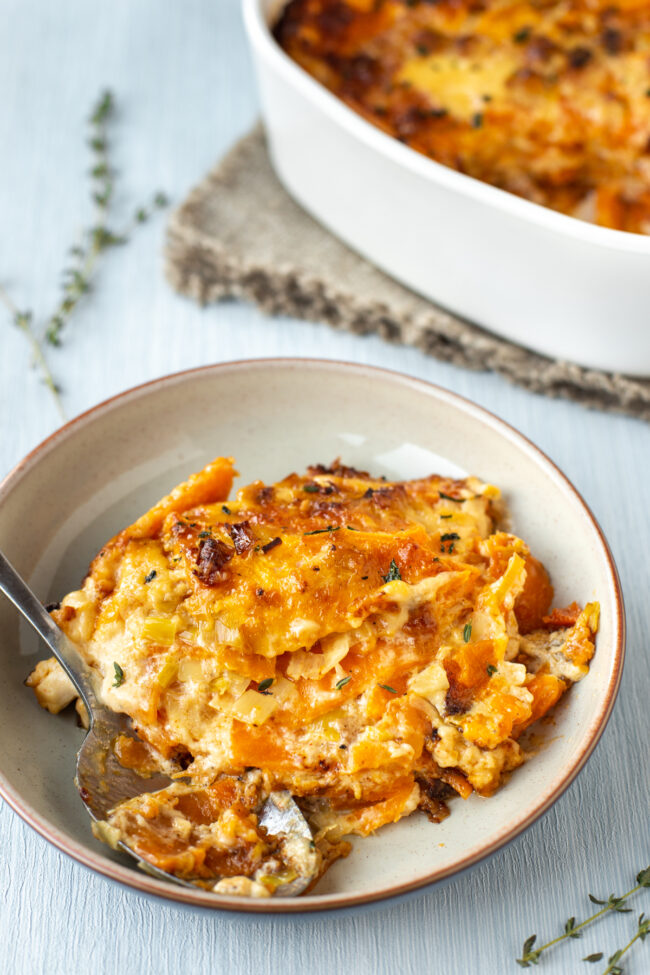 A portion of sweet potato gratin in a bowl with a spoon.