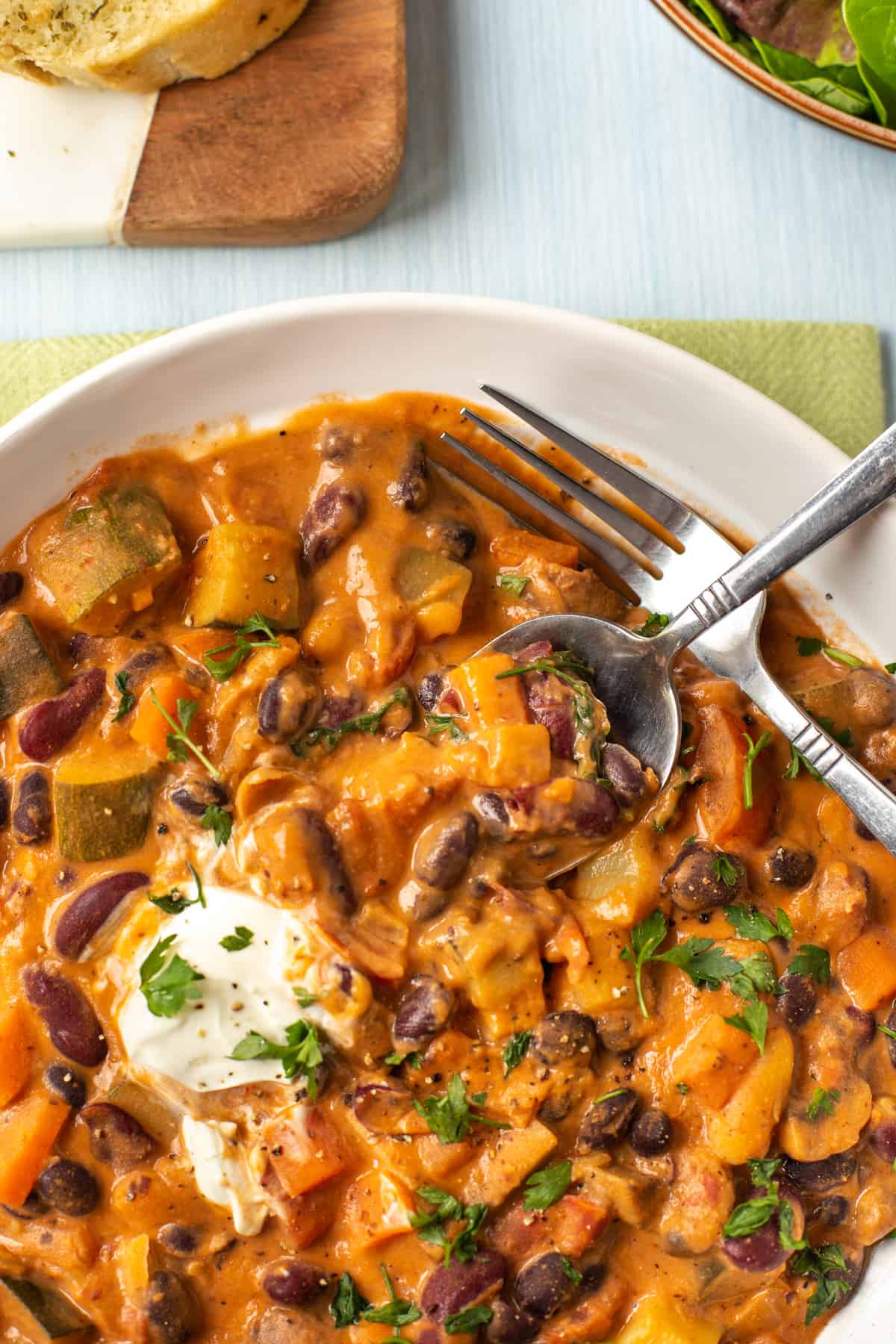 Close up photo of a spoon being dipped into a bowl of creamy bean stew.