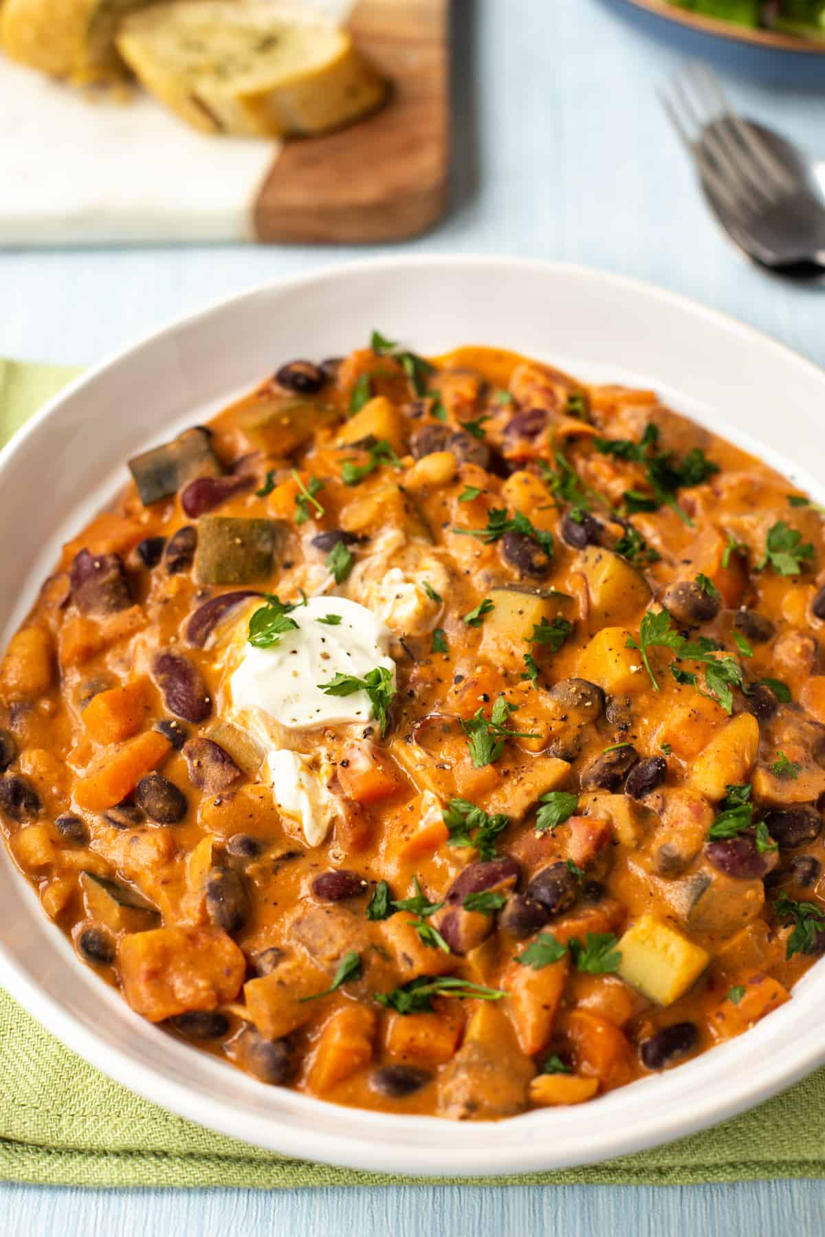 A bowlful of creamy vegetarian three bean stew topped with parsley and sour cream.