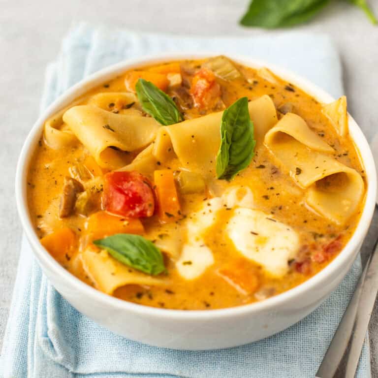 A bowl of vegetarian lasagne soup topped with fresh basil.
