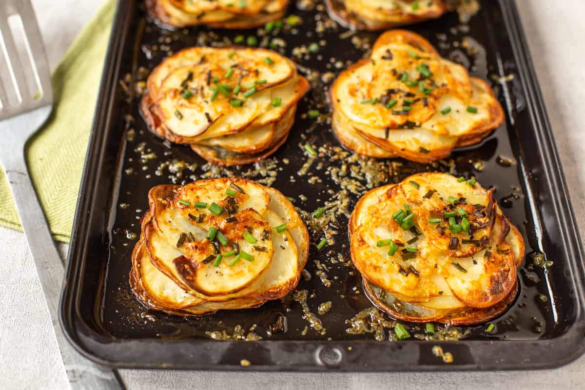Easy Cheesy Potatoes Anna on a baking tray, topped with chives and parmesan cheese.