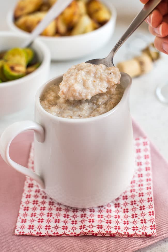A spoon scooping homemade bread sauce from a jug.