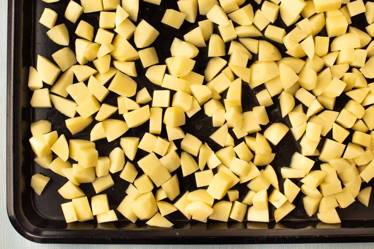 Raw potato cubes on a baking tray.