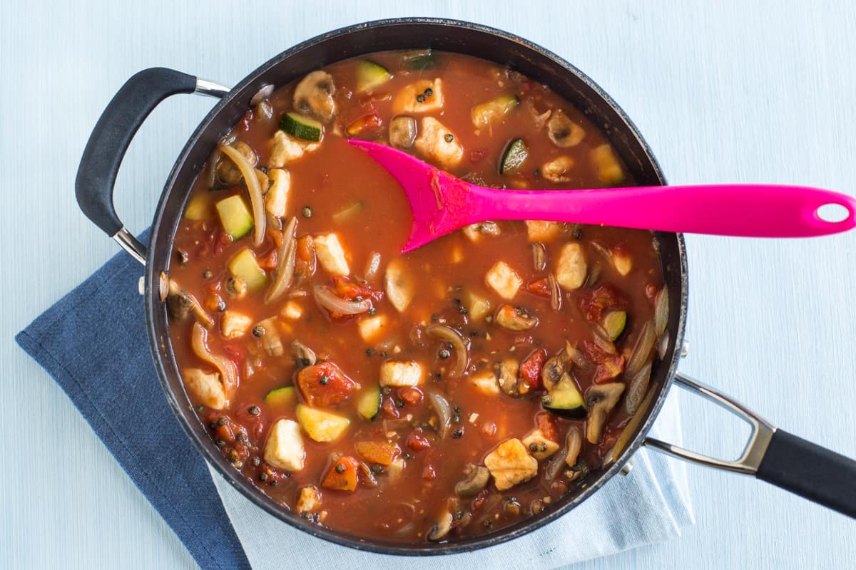 Lentil and halloumi curry being cooked with tomatoes and vegetable stock