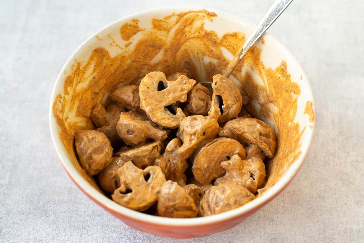 Mushrooms coated in tikka yogurt marinade in a bowl.