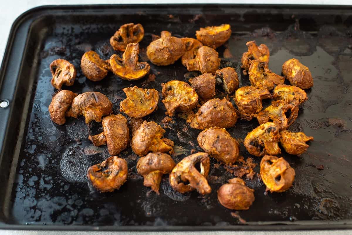 Mushroom tikka spread out on a baking tray.