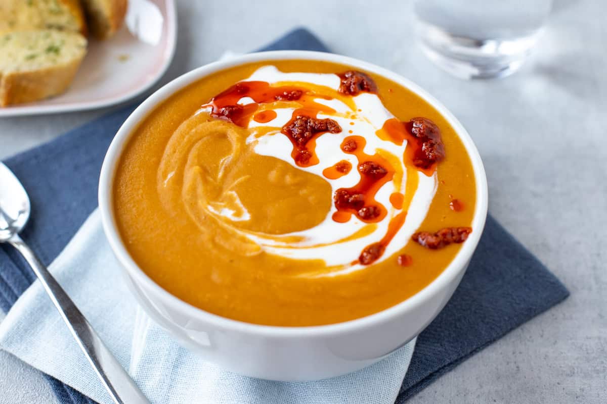 A bowl of creamy red lentil soup topped with red pesto.