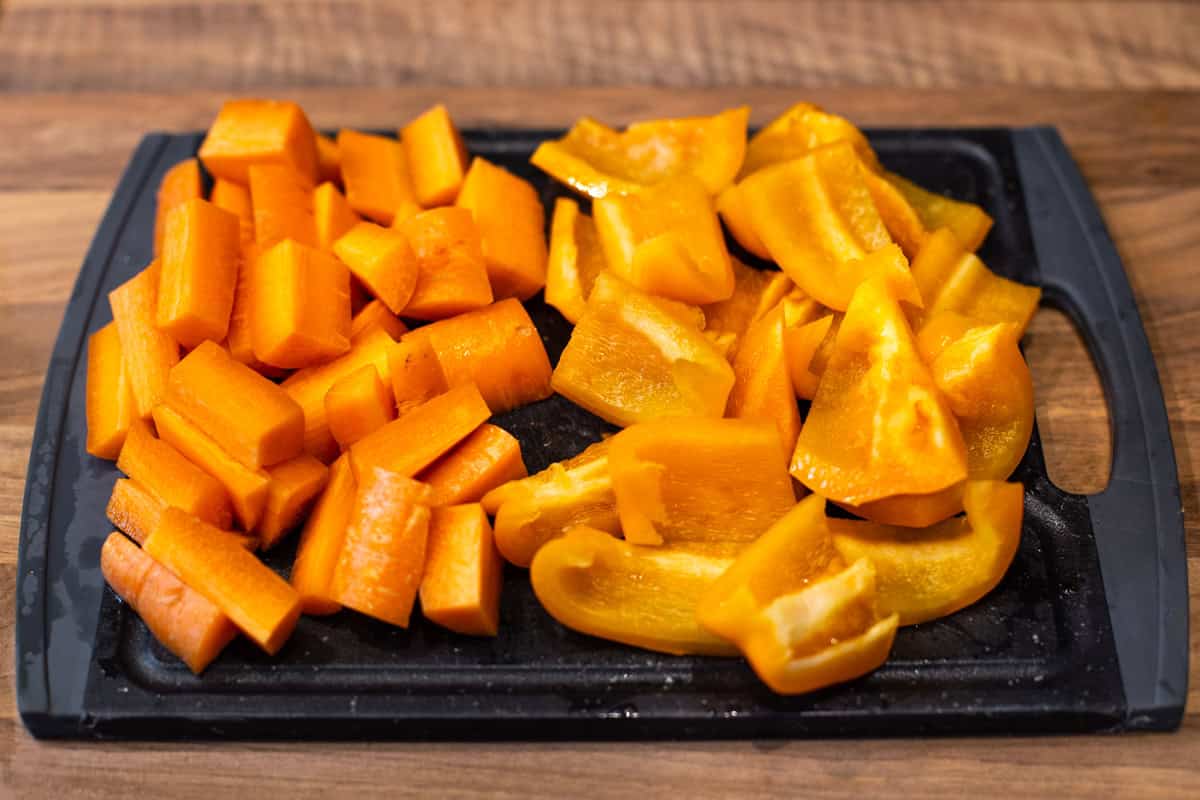Chopped carrots and peppers on a cutting board.