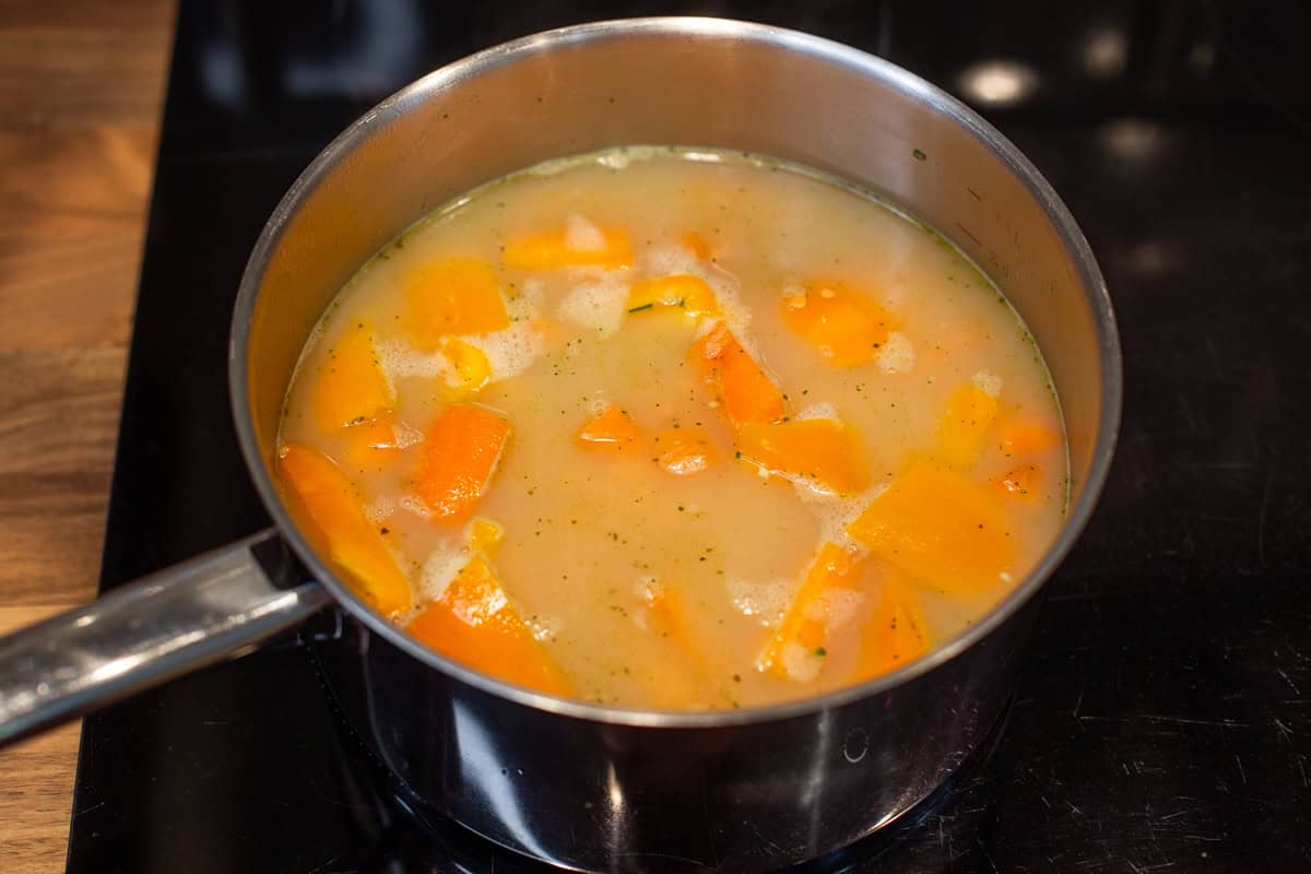 Vegetables and stock in a saucepan.