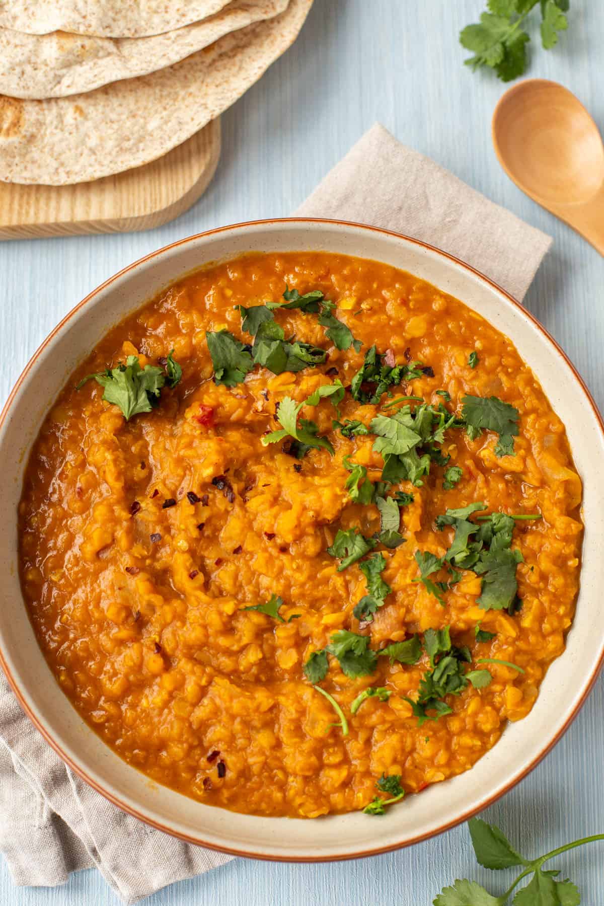 Bowl of tarka dal topped with cilantro, with chapattis on the side.