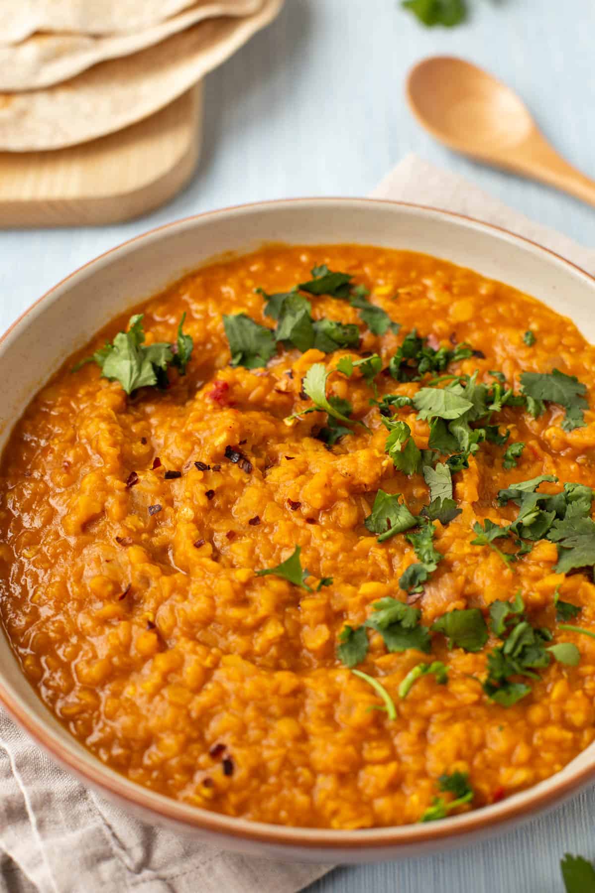 A bowlful of lentil curry with chapattis and cilantro.
