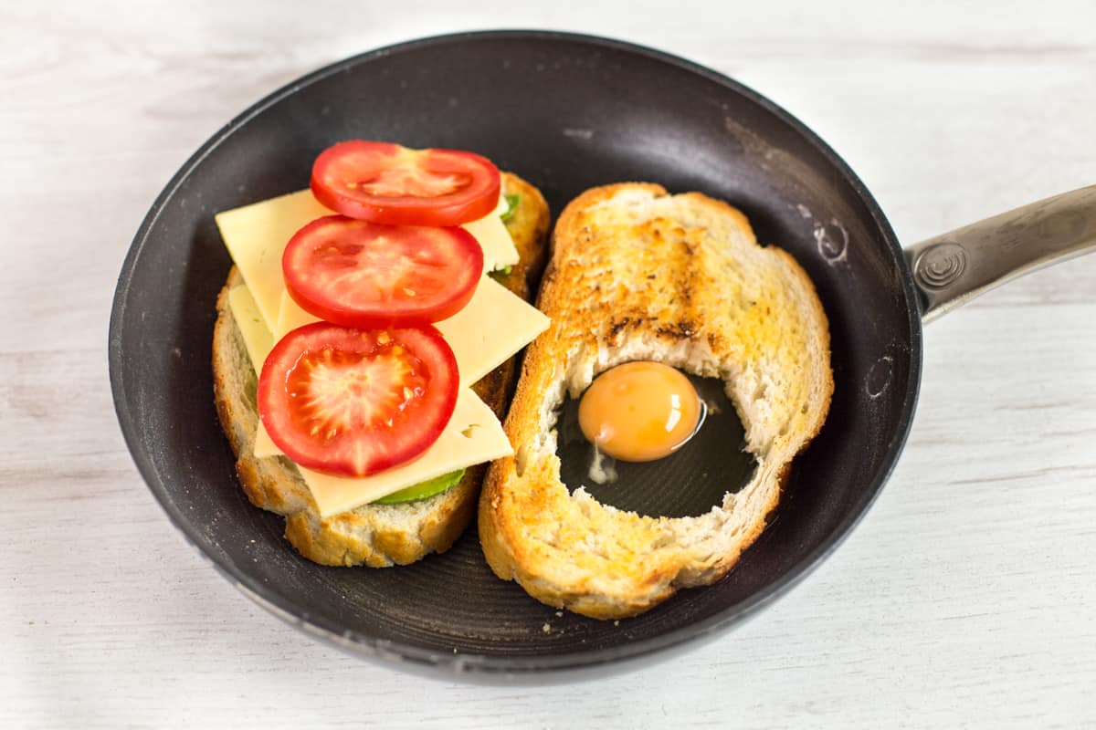 Toast in a frying pan, topped with cheese and sliced tomatoes.