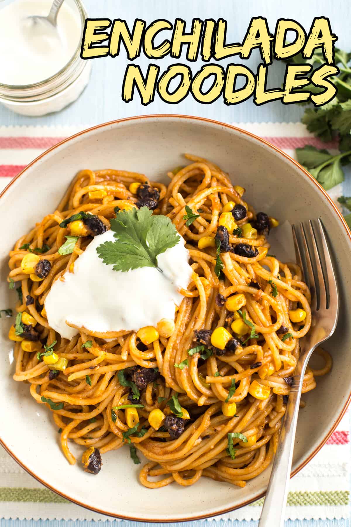 Portion of enchilada noodles in a bowl topped with sour cream and cilantro