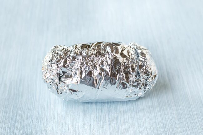 A foil packet containing a potato.
