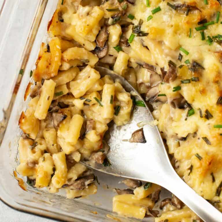 Garlic mushroom mac and cheese being scooped by a large spoon.