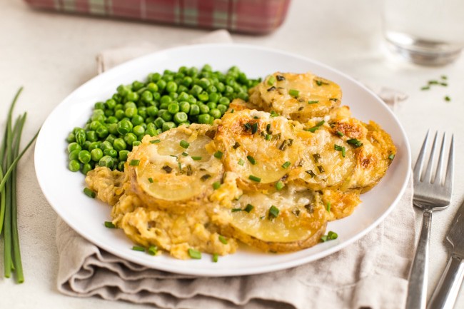 Portion of goat's cheese and potato lentil gratin on a plate with peas