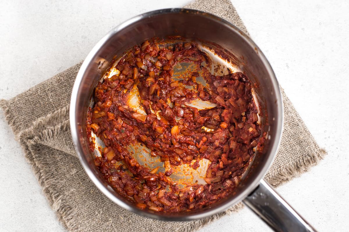Onions and tomato puree cooking in a small saucepan.