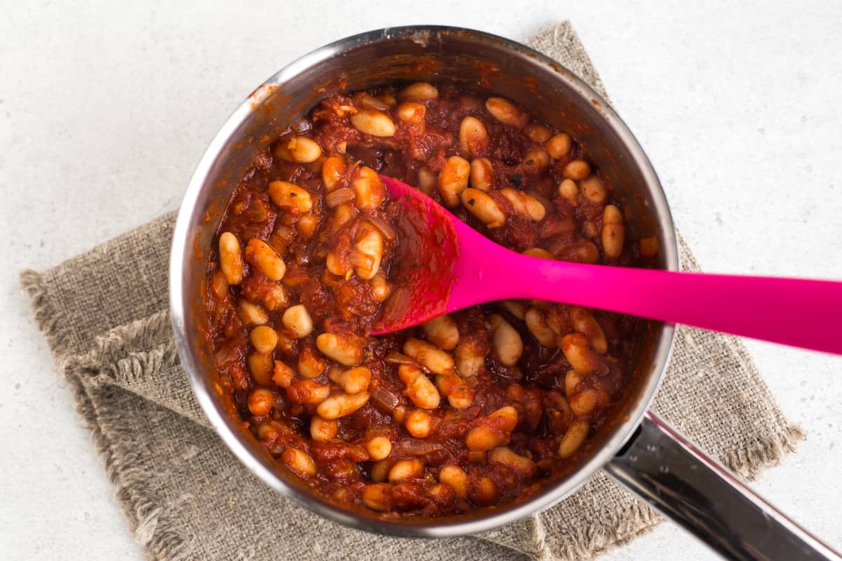 Homemade vegetarian baked beans cooking in a saucepan.
