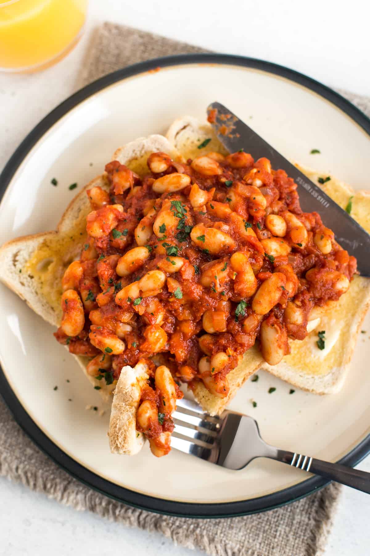 A fork taking a scoop of homemade baked beans on toast.
