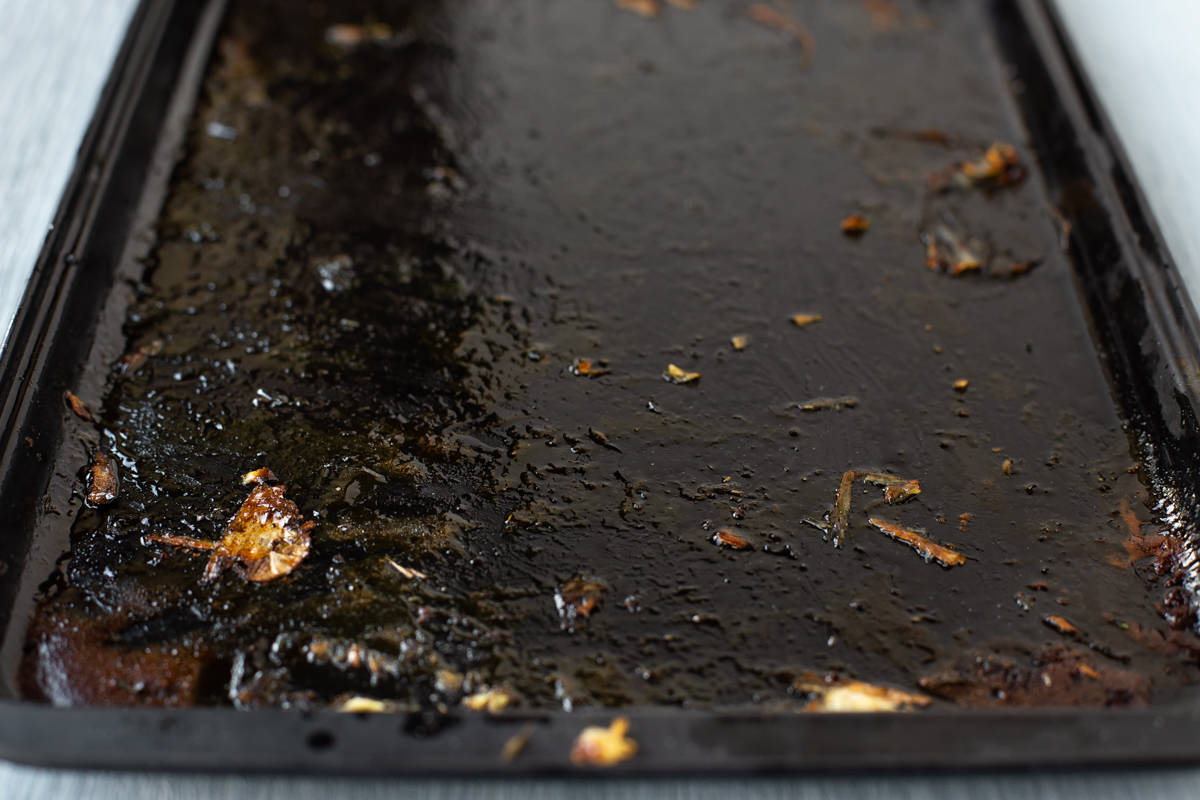 A baking tray that needs deglazing, covered in scraps of roasted vegetables and caramelised honey.