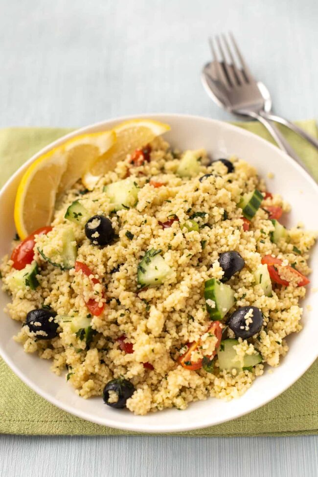 Couscous salad with black olives, cucumber, tomatoes, and lemon slices.