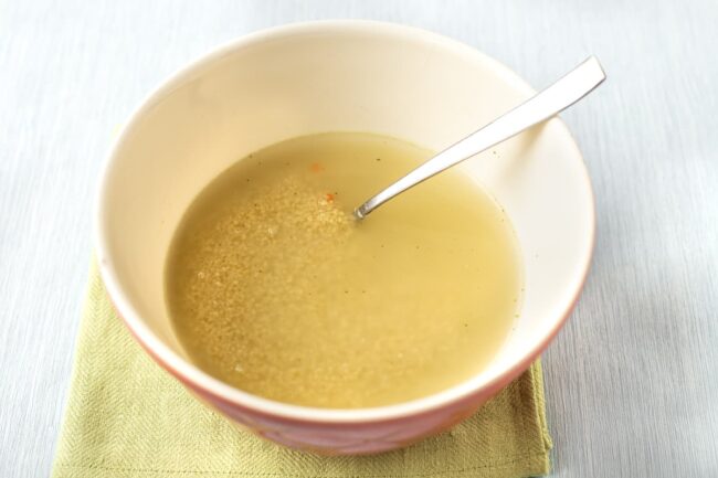 Dried couscous in a bowl with vegetable stock.